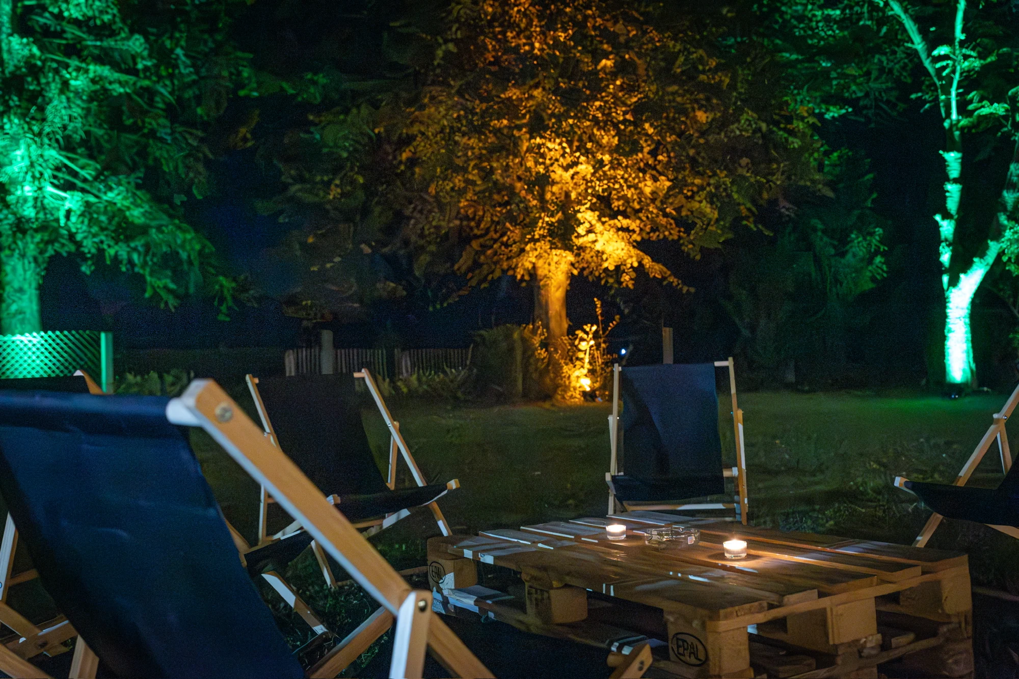 Liegestühle im beleuchteten Garten unter Bäumen